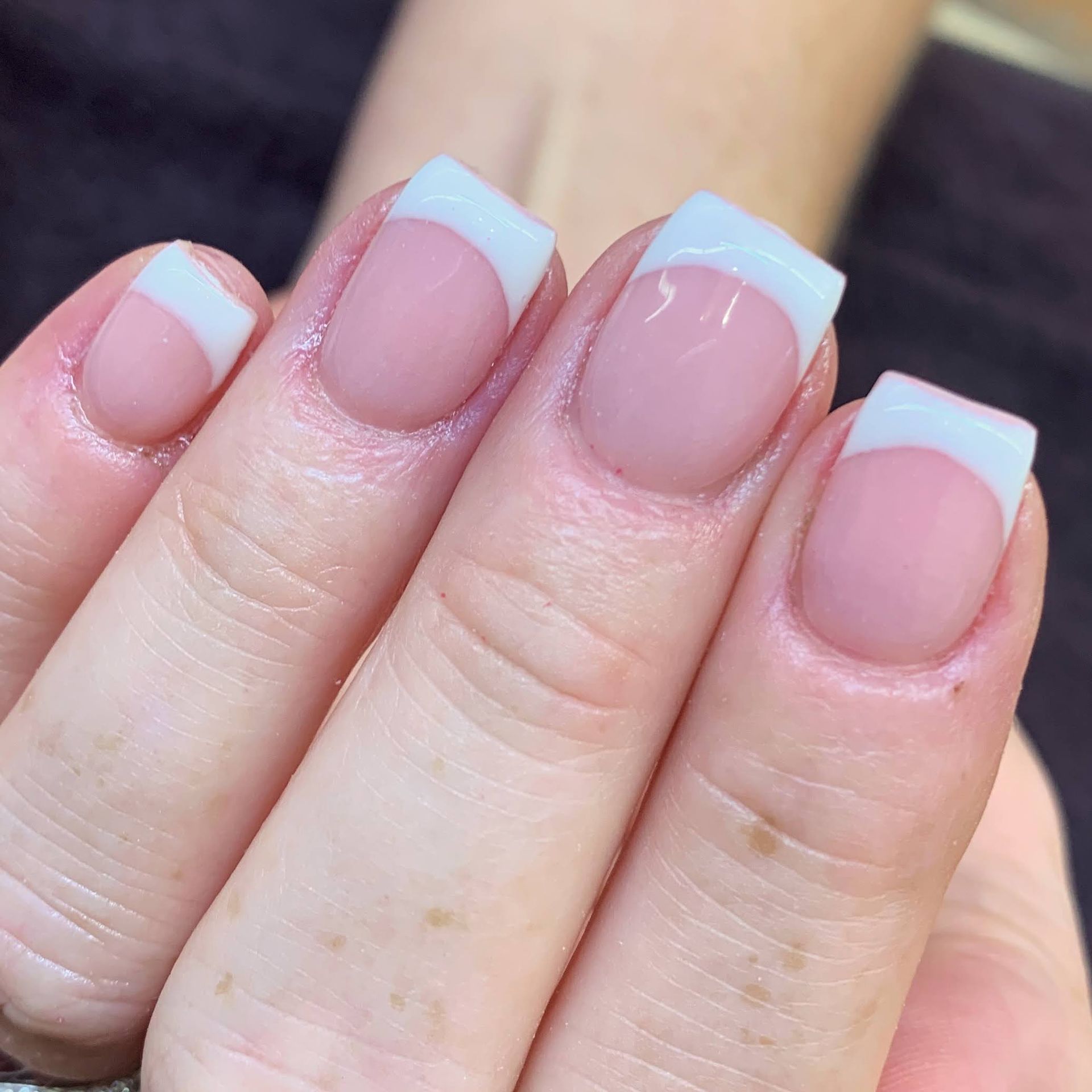 Close-up of red and white nail art with tiny hearts and black accents on manicured fingers