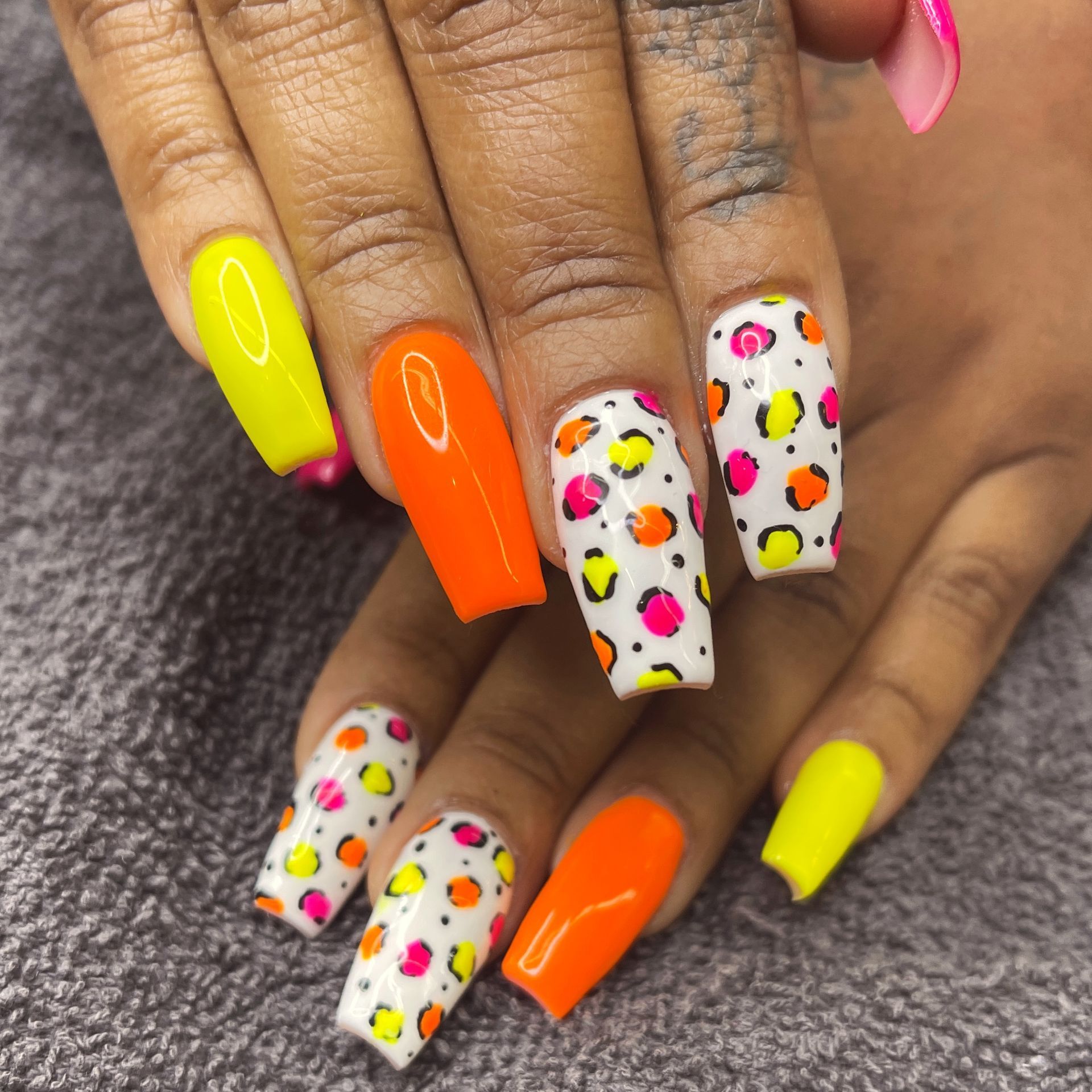Colorful manicure with neon yellow and orange nails and white nails decorated with multicolored sprinkles