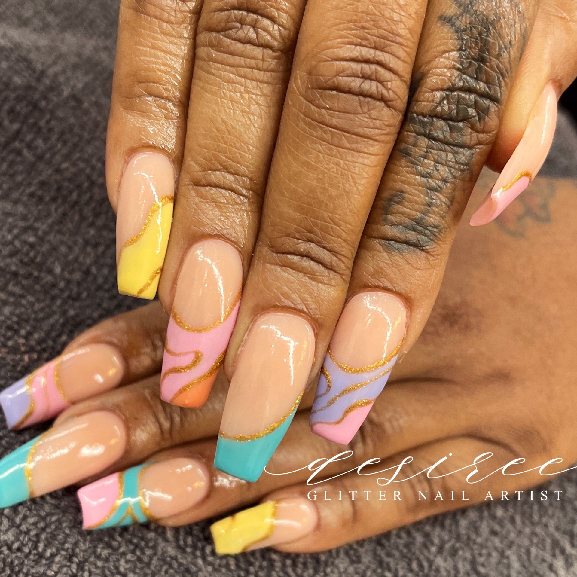 Hand with long pastel acrylic nails and gold wave accents, showing a colorful nail design.