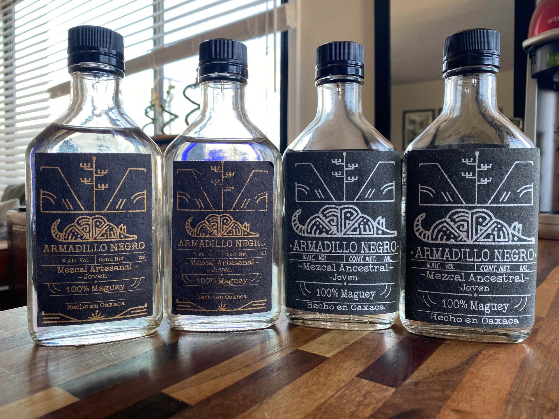 Four bottles of alcohol are sitting on a wooden table.
