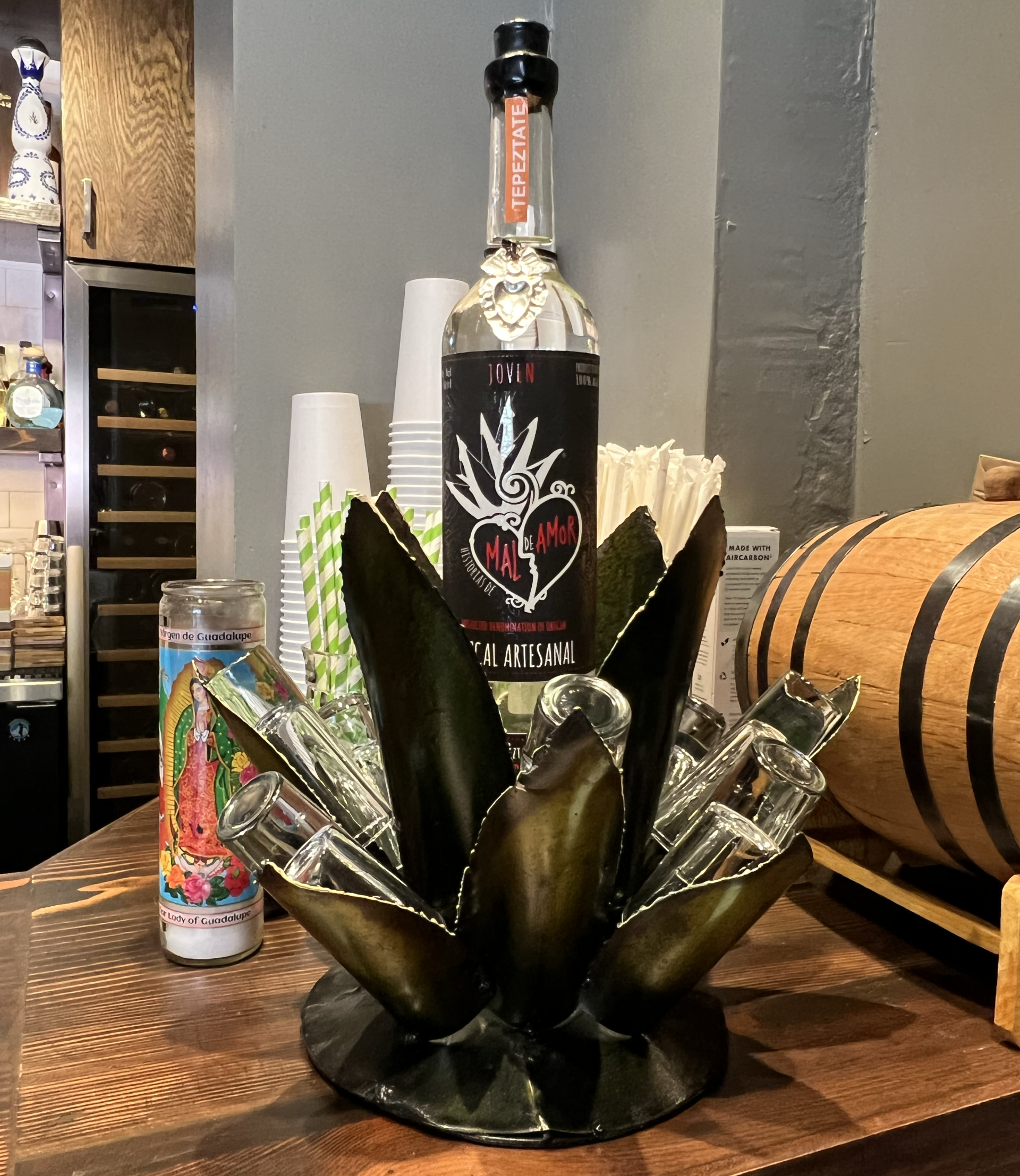 A bottle of tequila is sitting on a table next to a candle and a barrel.