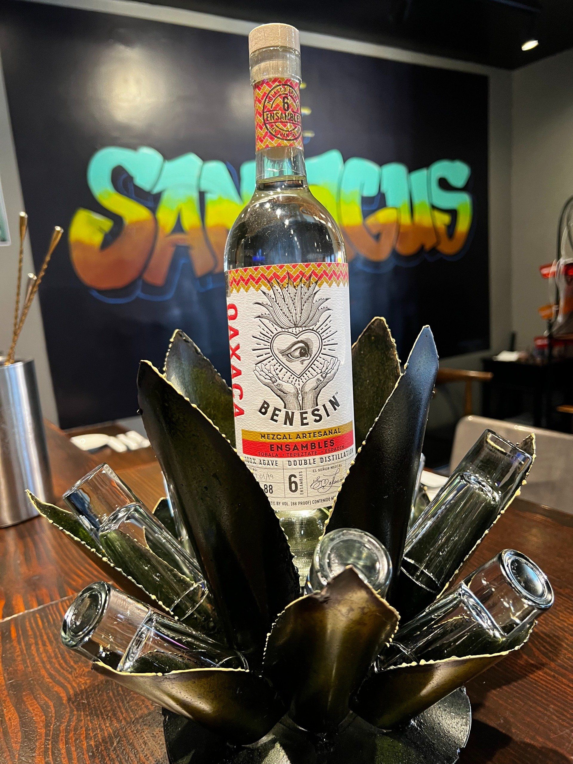 A bottle of tequila is sitting on top of a cactus on a table.
