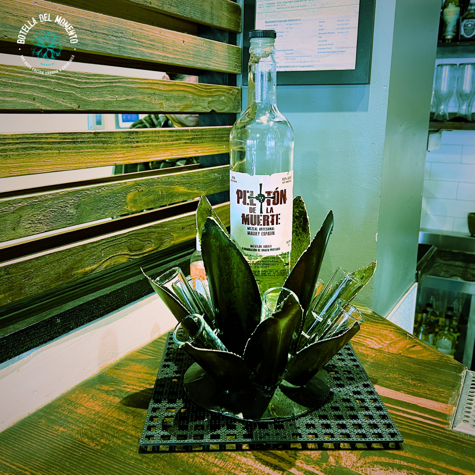 A bottle of mezcal sits on a wooden table