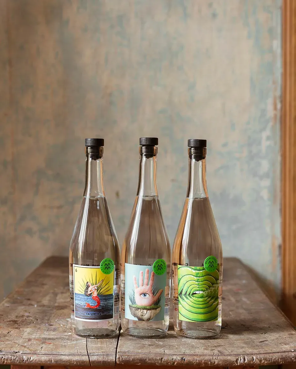Three bottles of alcohol are sitting on a wooden table.