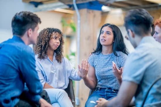 Small group in a casual meeting, talking and listening in a bright office lounge.