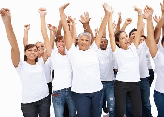 Group of people in white shirts raising their arms and smiling in celebration