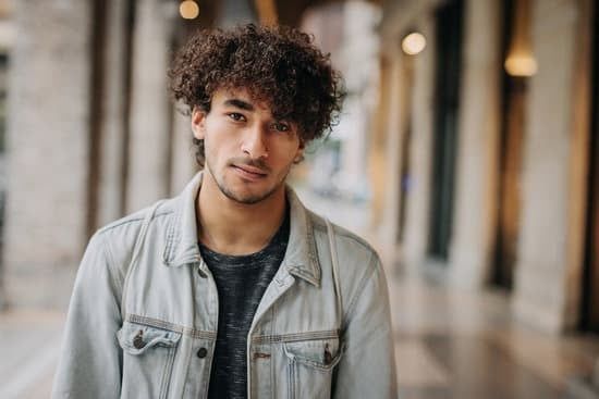 Young man in a light denim jacket standing in a blurred indoor corridor