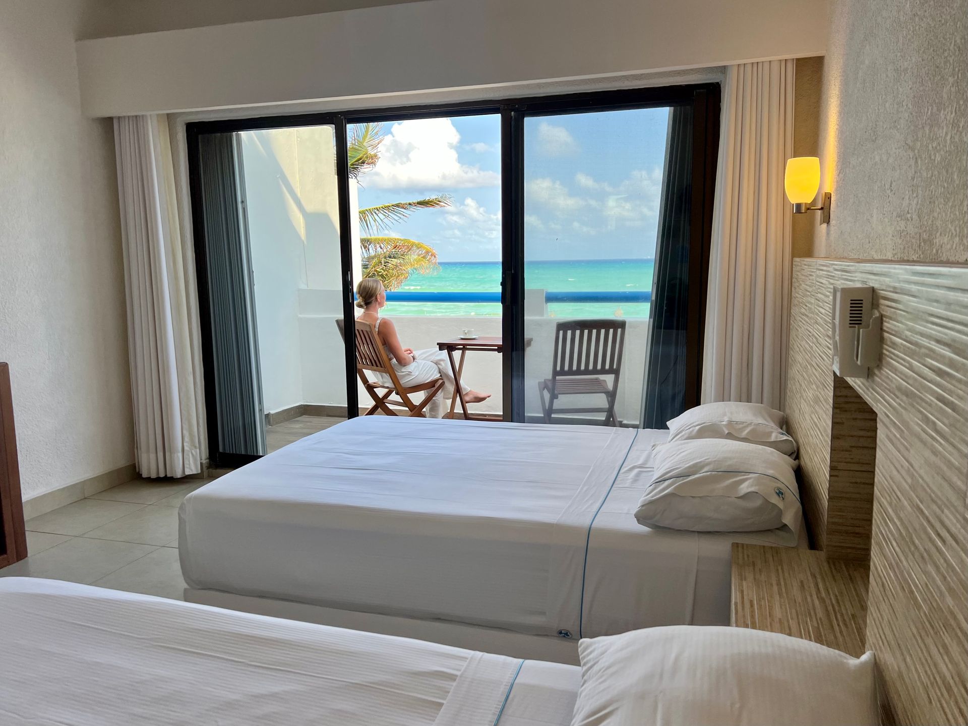 Una habitación de hotel con dos camas y un balcón con vista al mar.