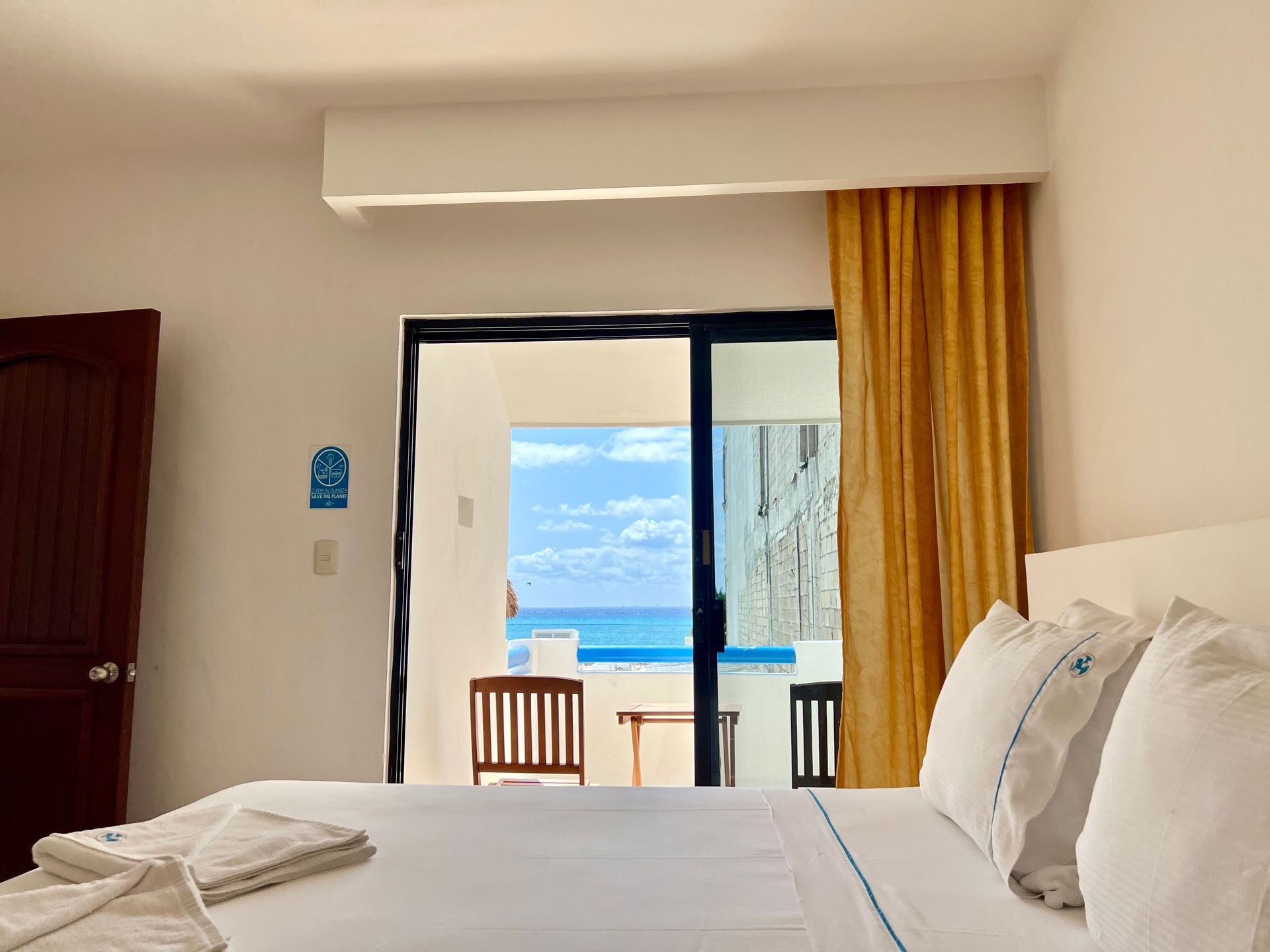 Un dormitorio con una cama grande y una puerta corrediza de vidrio que conduce a un balcón con vista al océano.