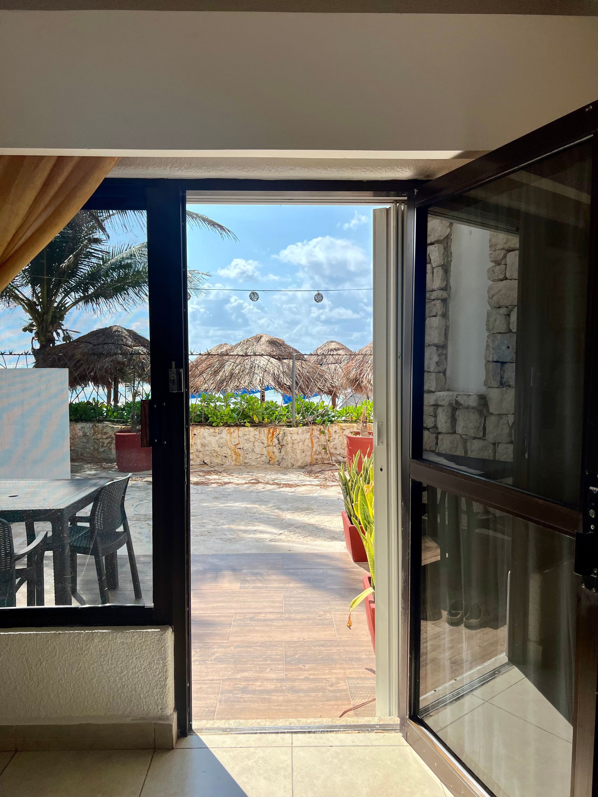 La puerta está abierta a un patio con sombrillas y una mesa y sillas.