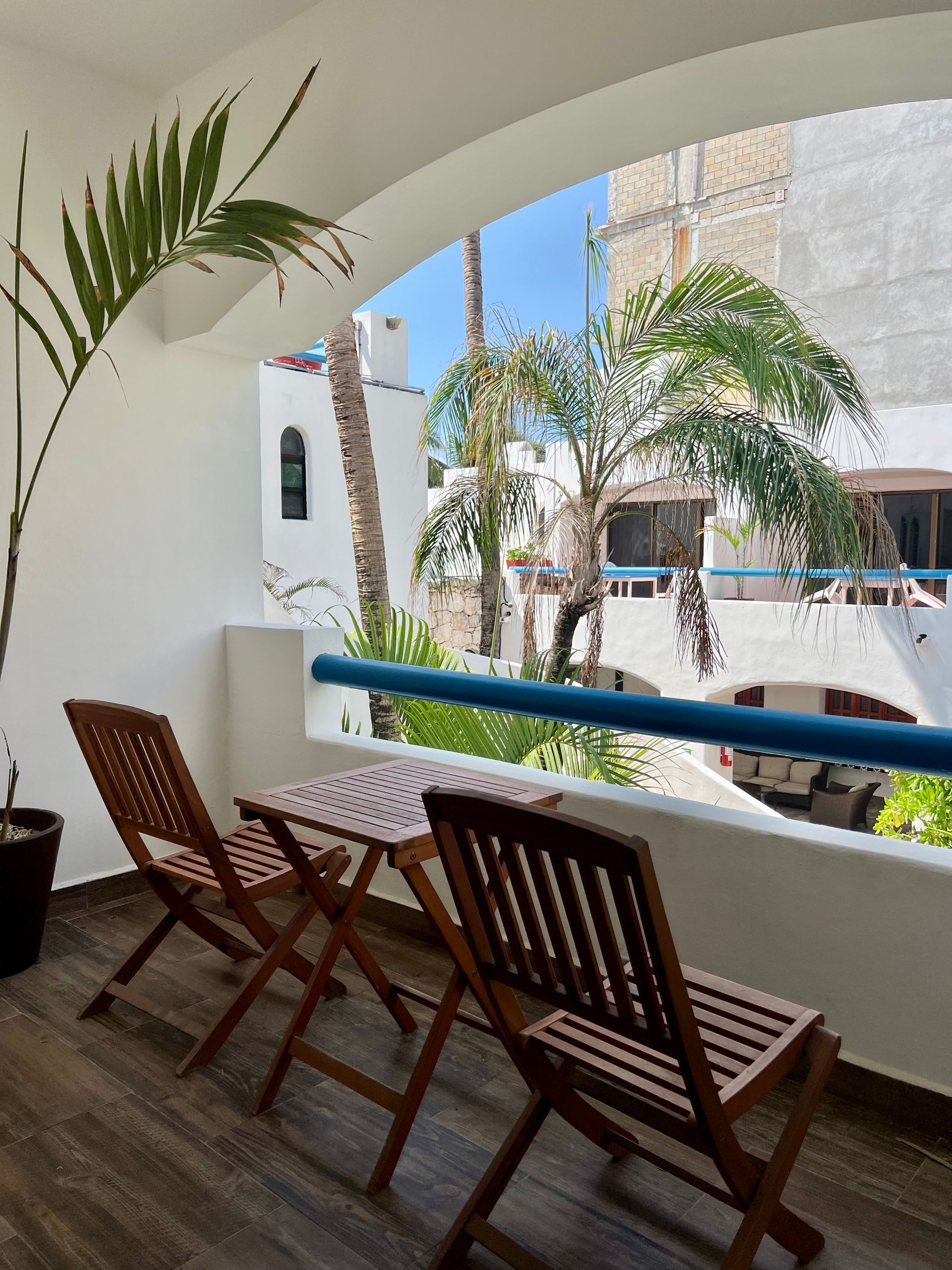 Un balcón con mesa y sillas con vista a las palmeras.