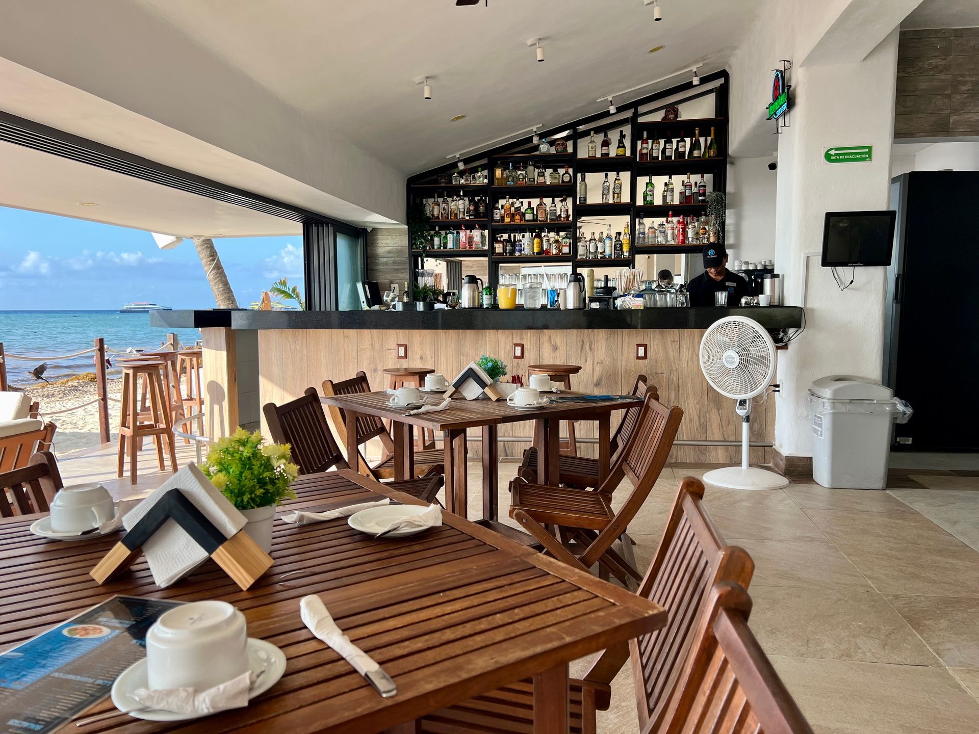 Un restaurante con mesas y sillas y un bar con vista al mar.