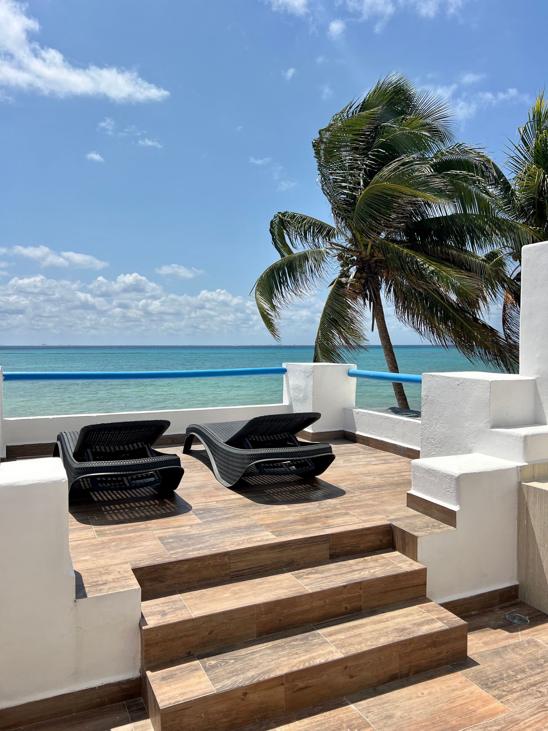 Un patio con sillas y escaleras con vista al mar.