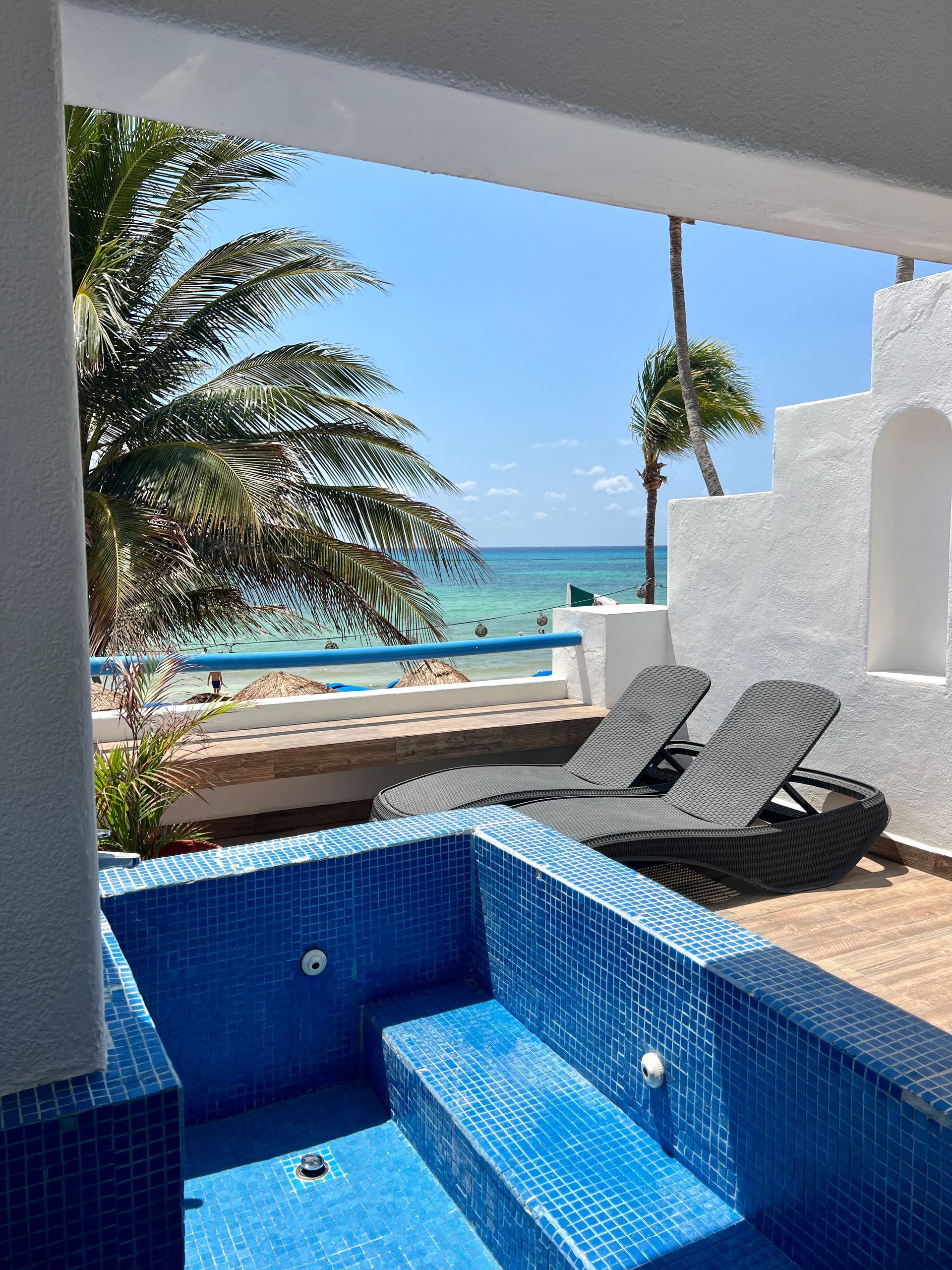Un jacuzzi azul en un balcón con vista al océano.