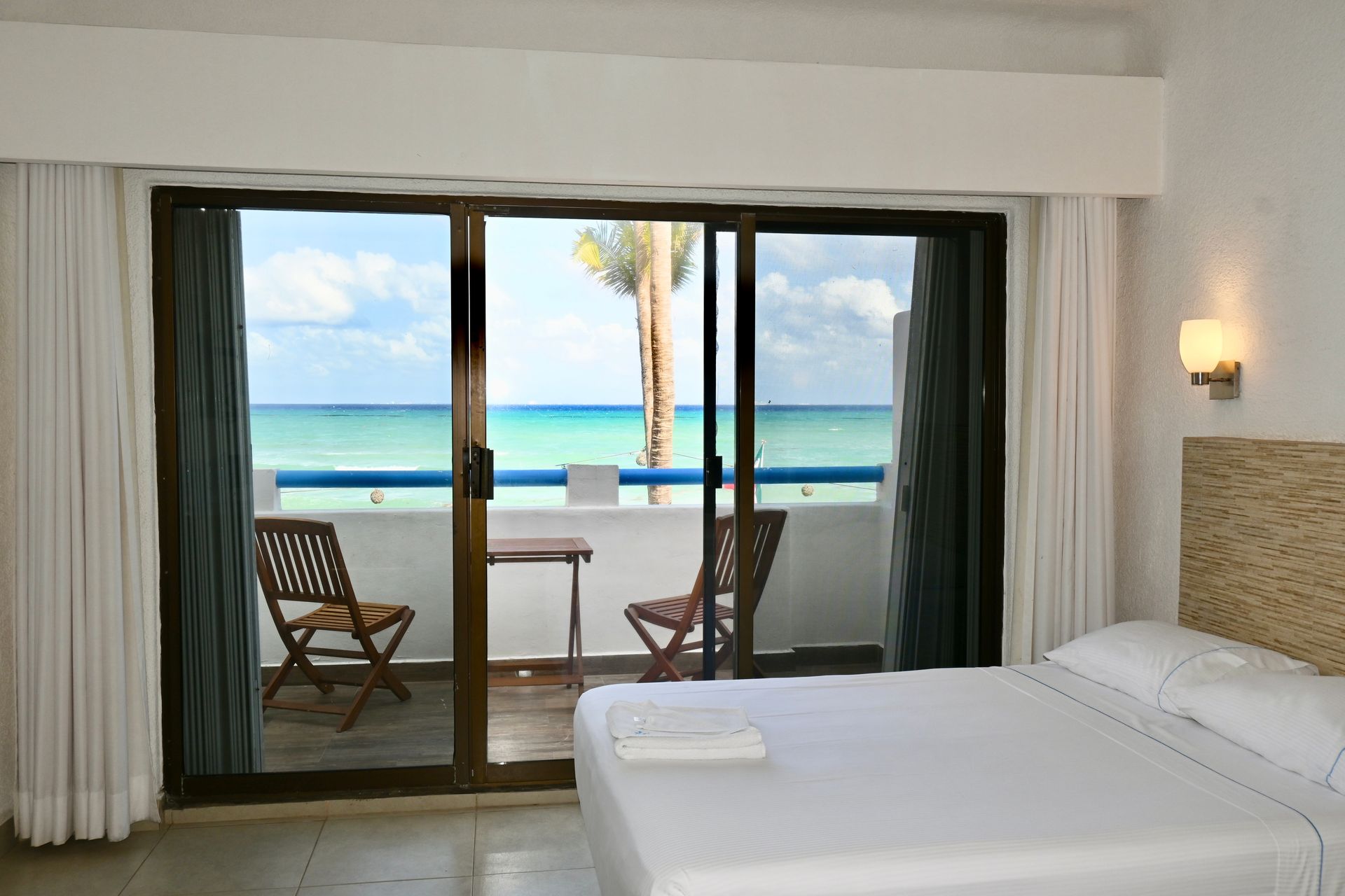 Una habitación de hotel con una cama king size y un balcón con vista al océano.