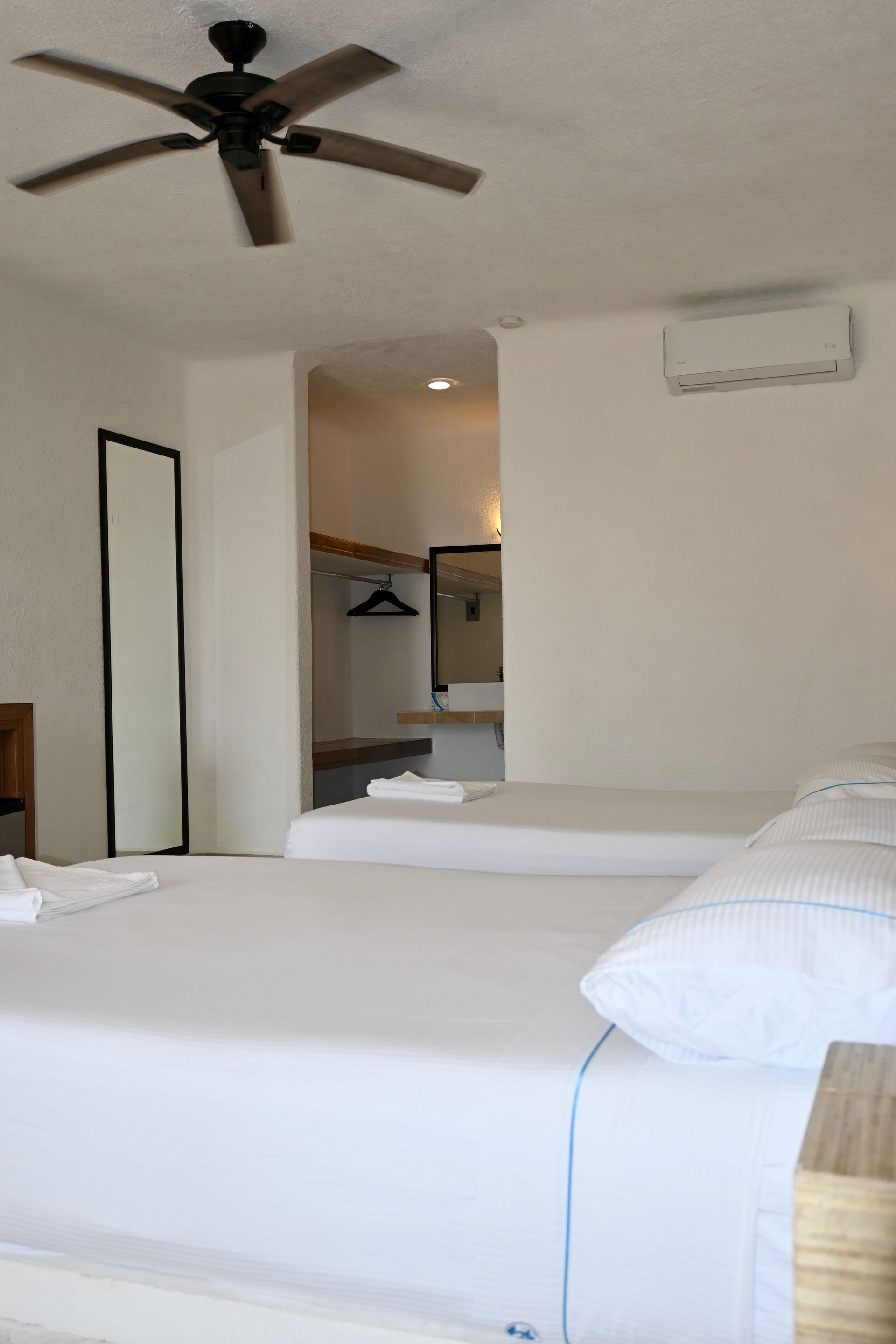 Una habitación de hotel con dos camas y un ventilador de techo.