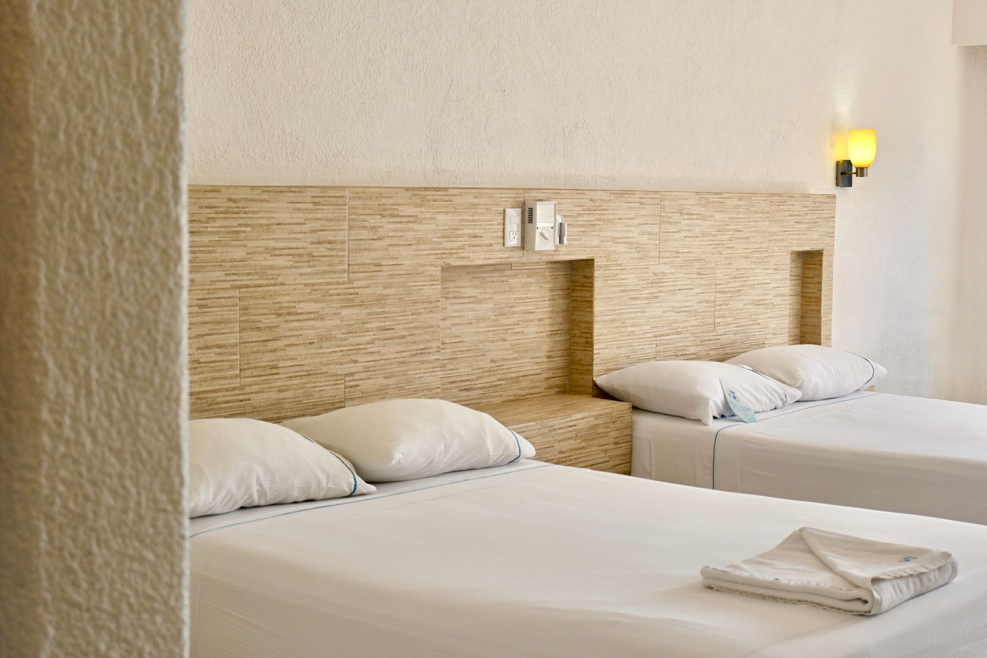 Una habitación de hotel con dos camas y un cabecero de madera.