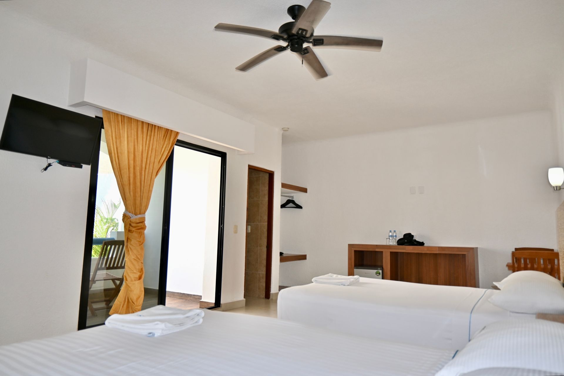 Una habitación de hotel con dos camas y un ventilador de techo.