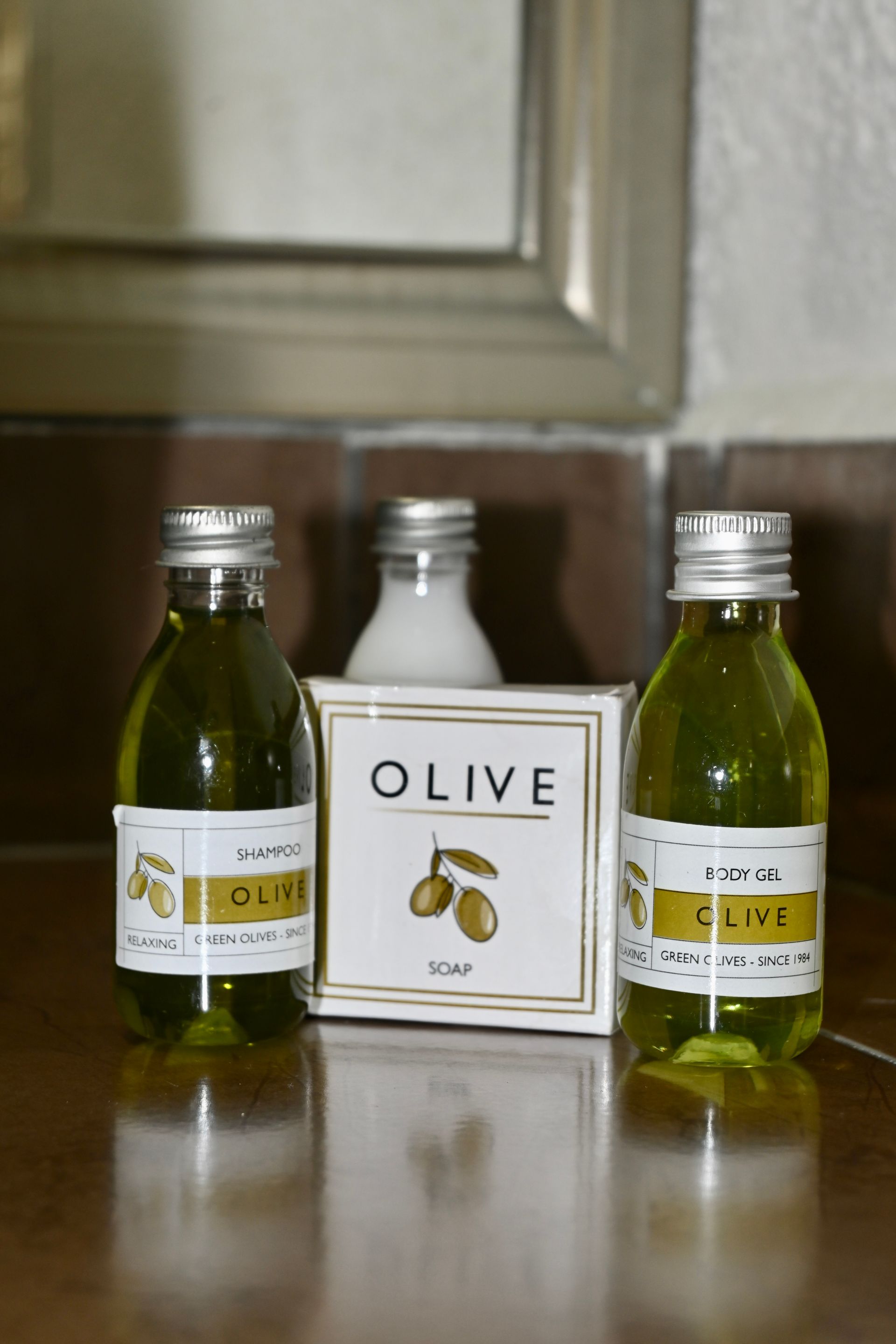 Dos botellas de aceite de oliva y una caja de jabón de oliva sobre una mesa.
