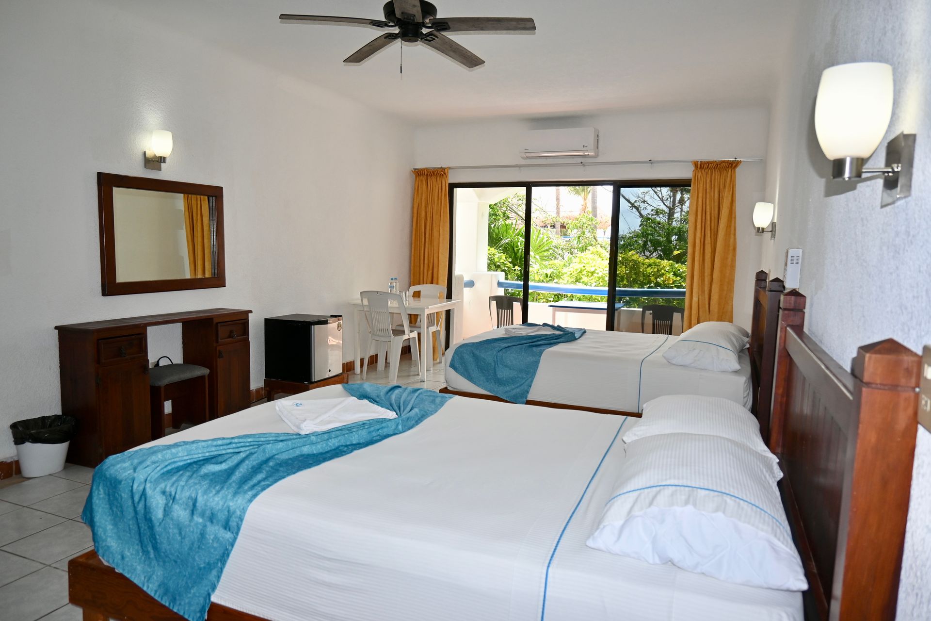 Una habitación de hotel con dos camas y un ventilador de techo.