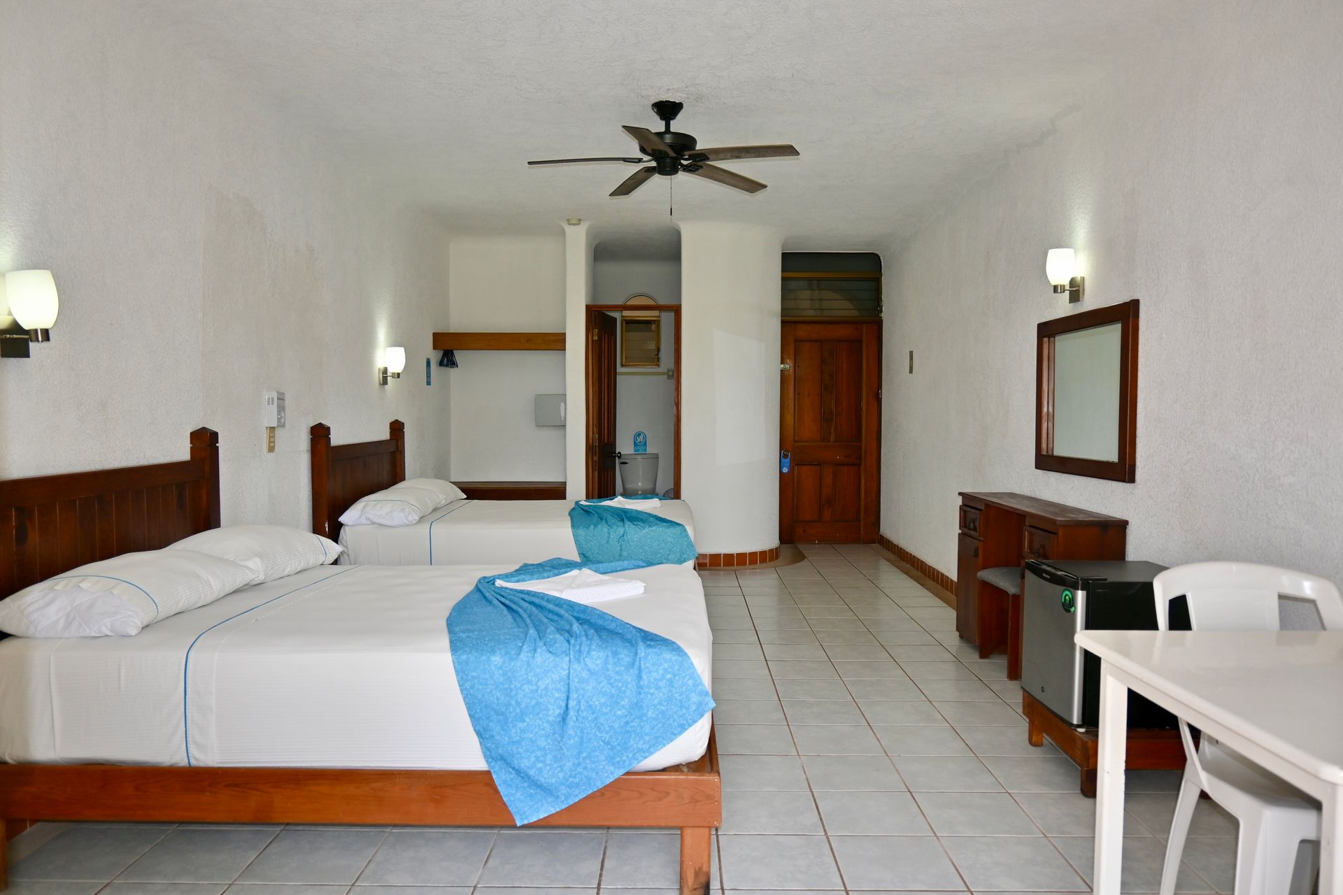 Una habitación de hotel con dos camas y un ventilador de techo.