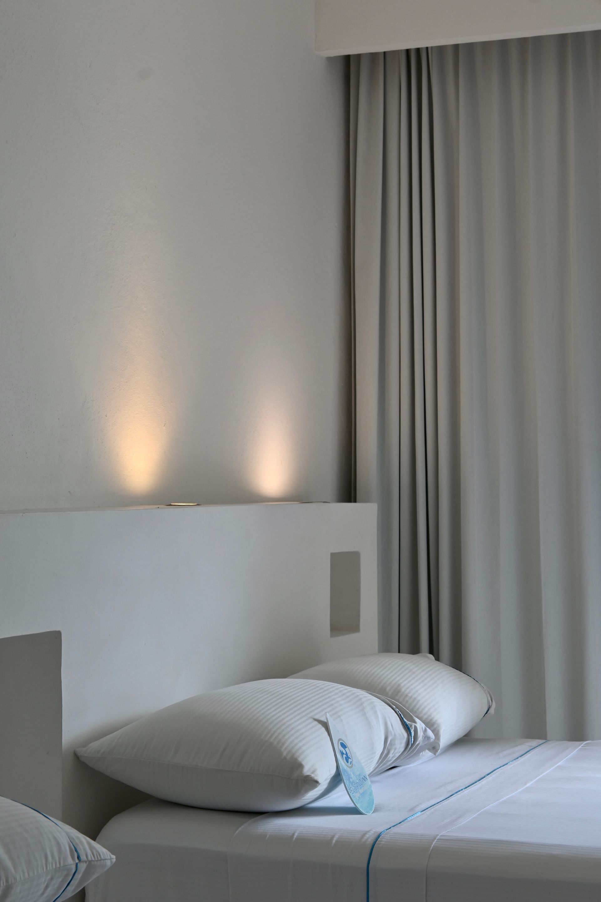 Una cama con sábanas blancas y almohadas en una habitación de hotel.