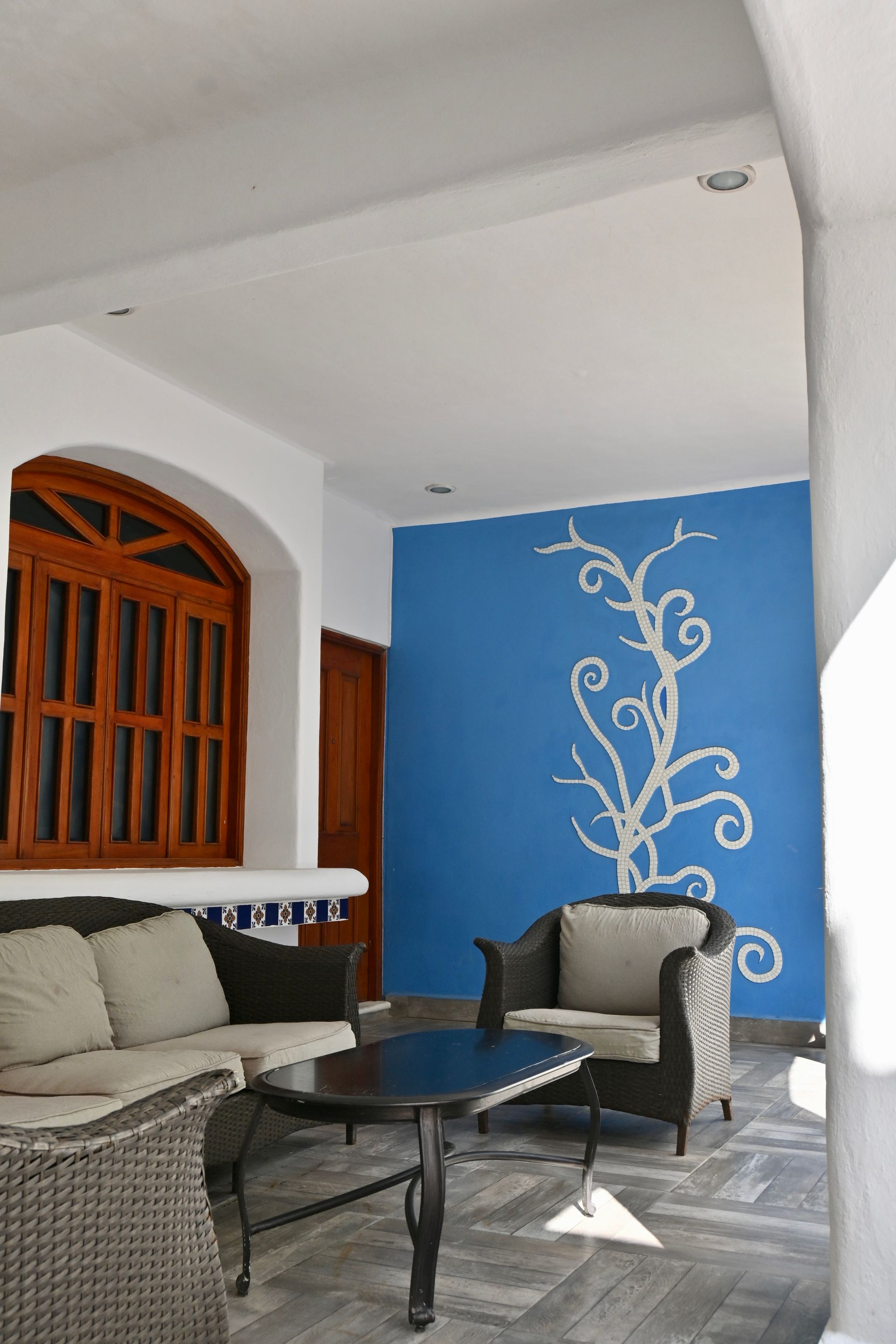 Zona de estar al aire libre con una pared con acento azul y un patrón decorativo de enredaderas.