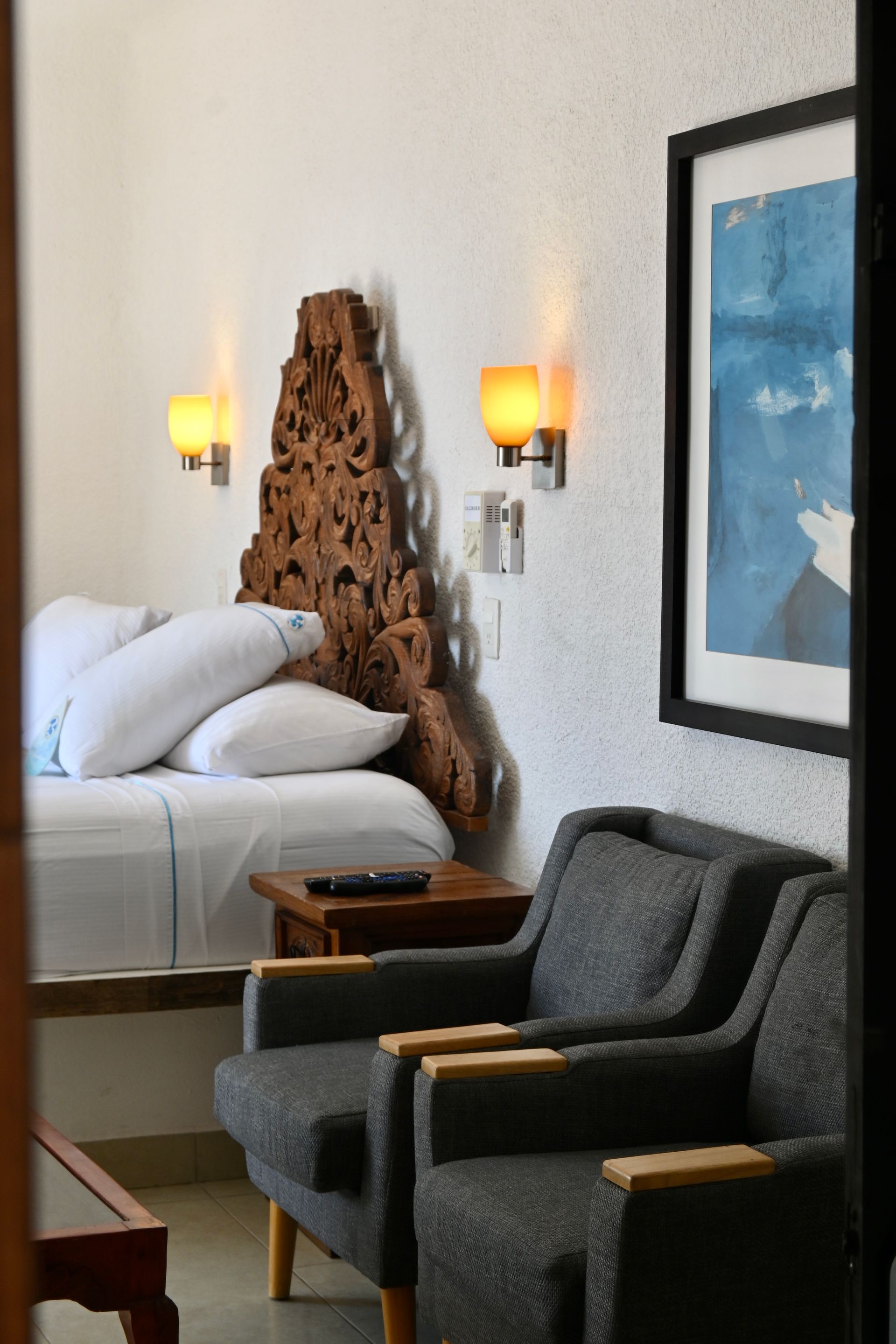 Un dormitorio con una cama y sillas y un cuadro en la pared.