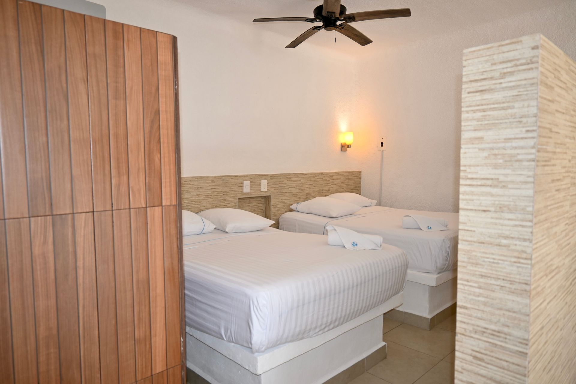 Una habitación de hotel con dos camas y un ventilador de techo.