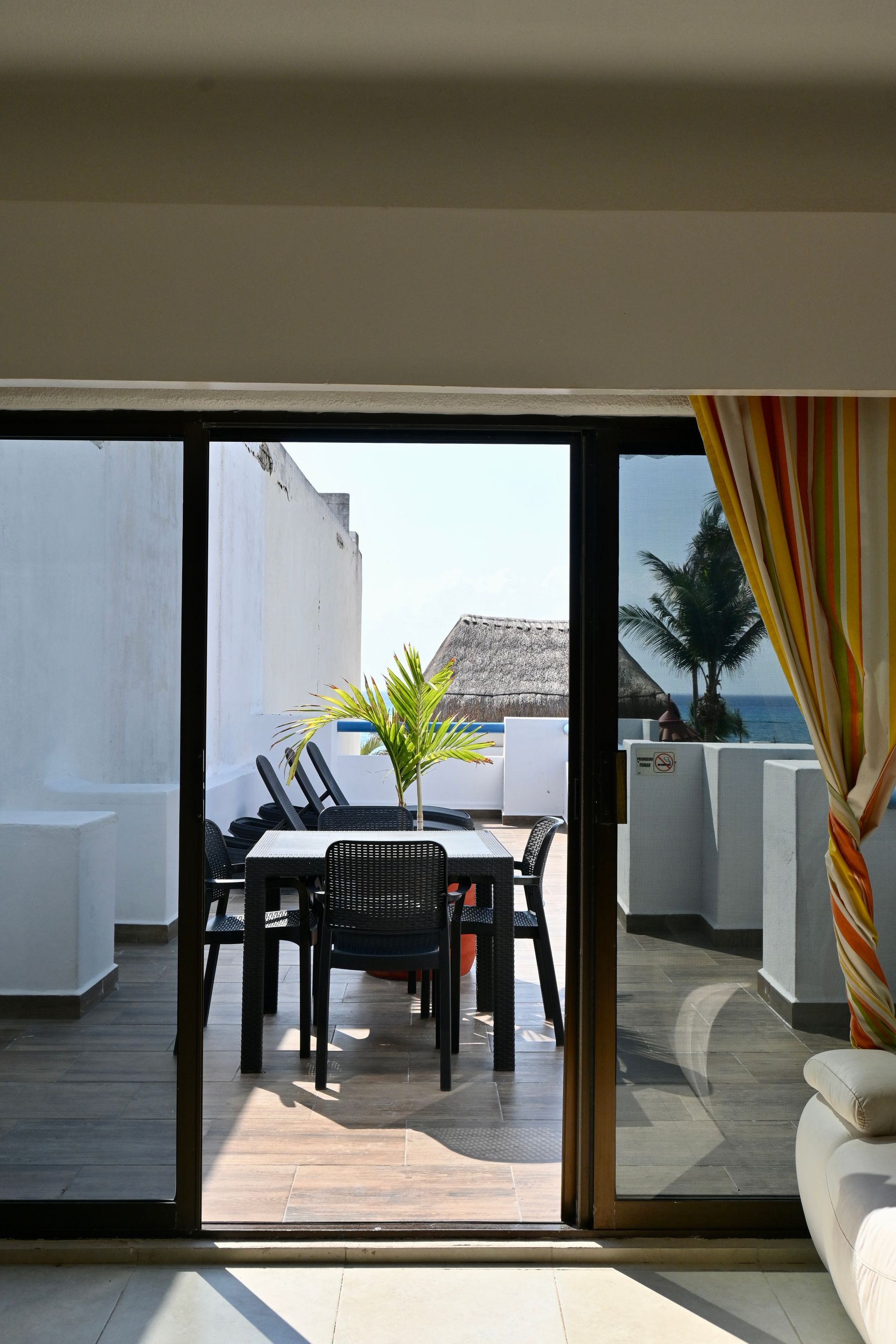 Un patio con una mesa y sillas es visible a través de una puerta corrediza de vidrio.
