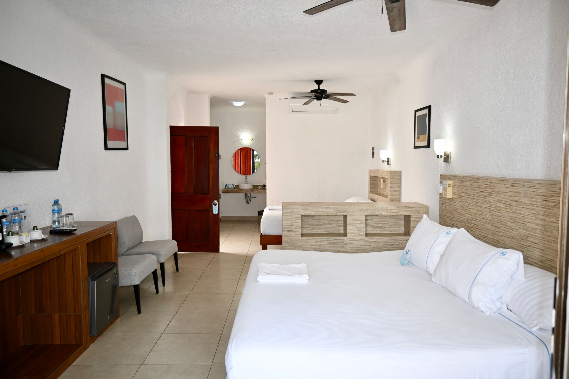 Una habitación de hotel con dos camas, un televisor y un ventilador de techo.