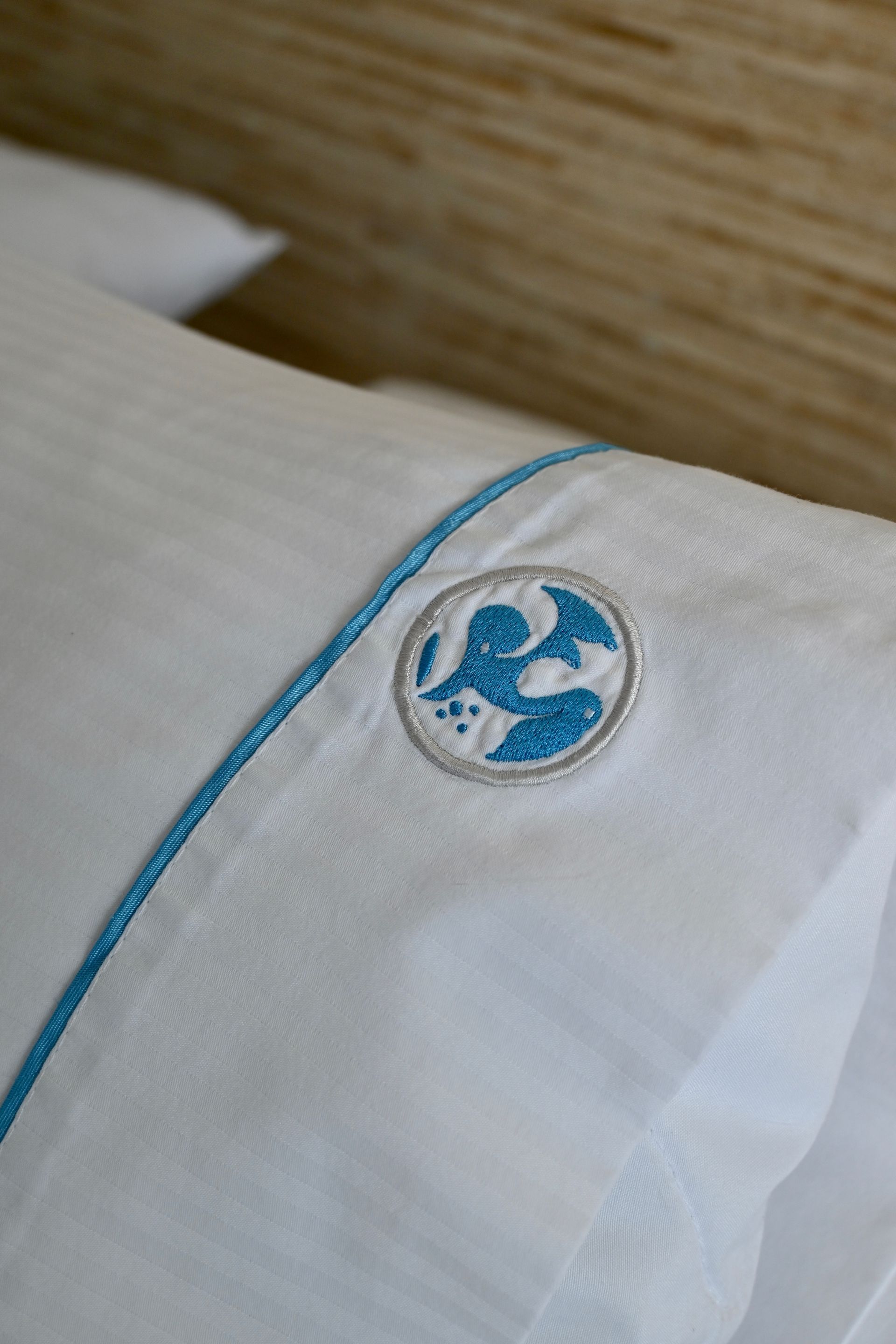 Un primer plano de una almohada blanca con un logotipo azul bordado en ella.