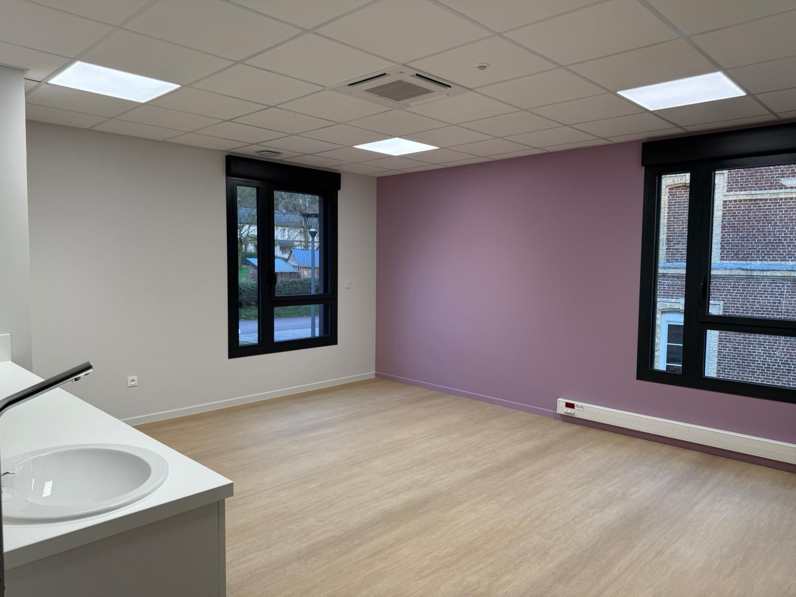 Une pièce vide avec des murs violets et un lavabo avec notre entreprise de peinture normandie.