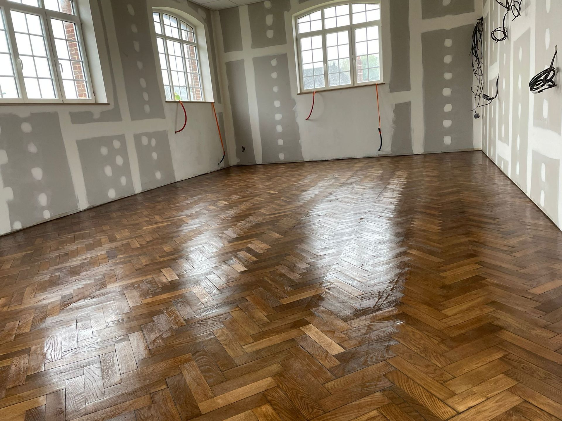 Une pièce avec un plancher en bois et beaucoup de fenêtres avec notre entreprise de peinture normandie.