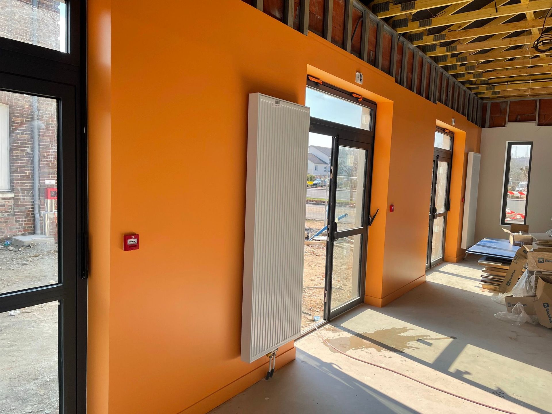 Un bâtiment en construction avec des murs orange et des fenêtres noires avec notre entreprise de peinture normandie