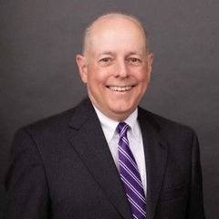 Man in suit with purple striped tie smiles at the camera.
