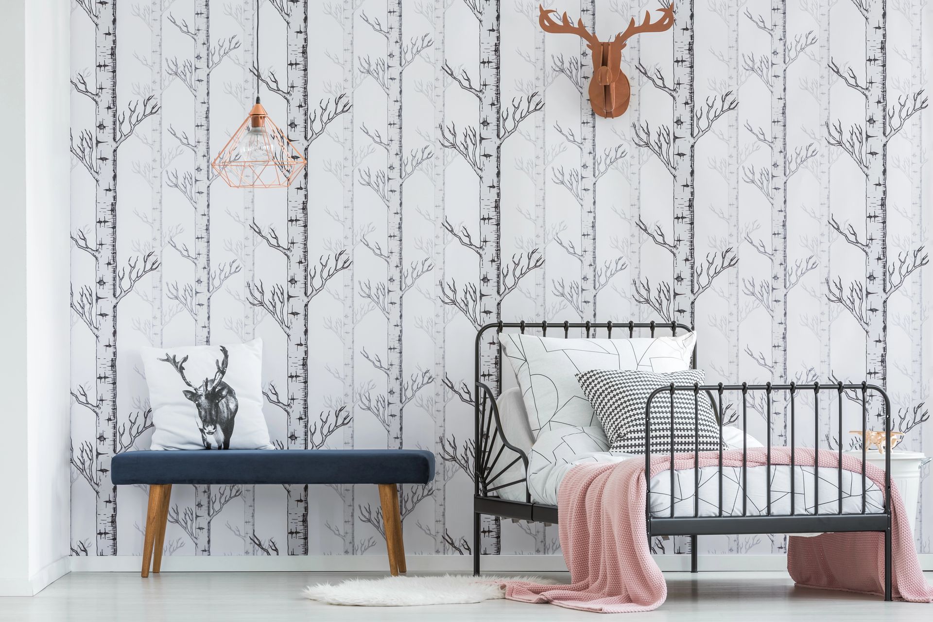 Bedroom with birch tree wallpaper, black bed frame, pink blanket, and a deer head decor.