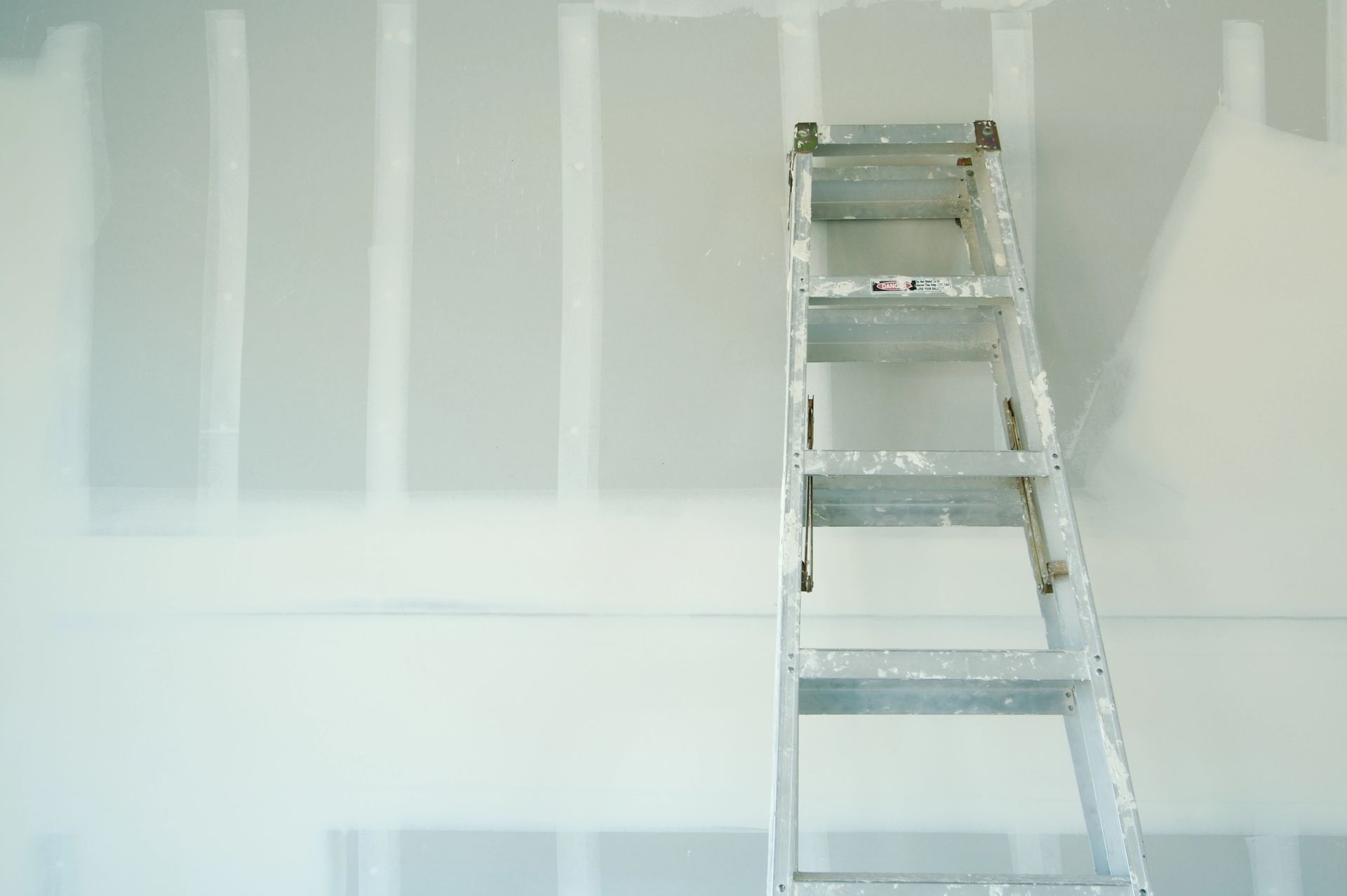 Ladder leaning against a wall during construction, with exposed studs and drywall in Madison, Wisconsin.