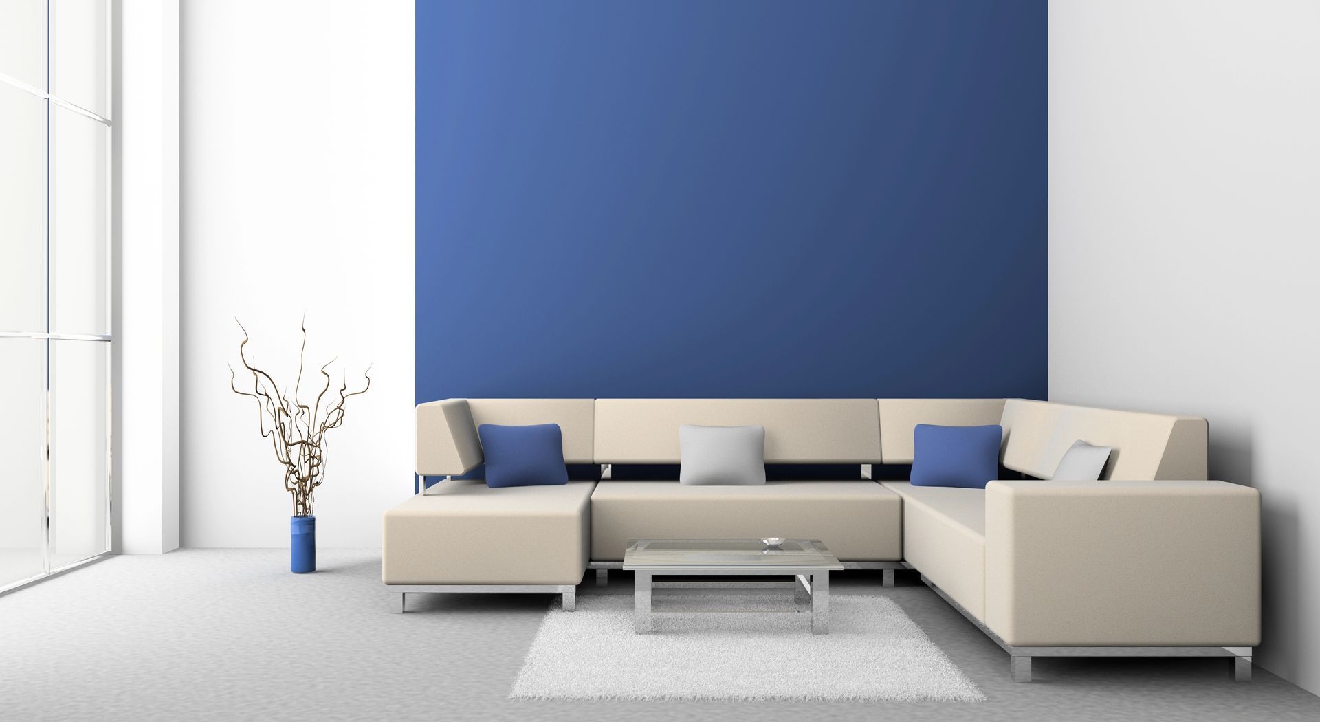 Beige sectional sofa against a blue accent wall; white rug, vase with branches.