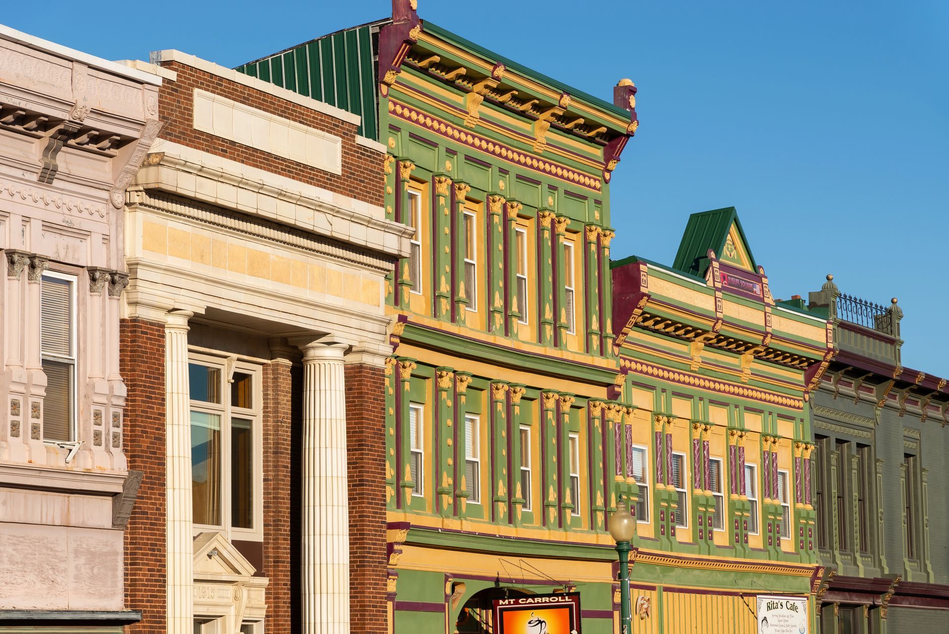 Colorful historic buildings with detailed facades and ornate trim under a clear blue sky.