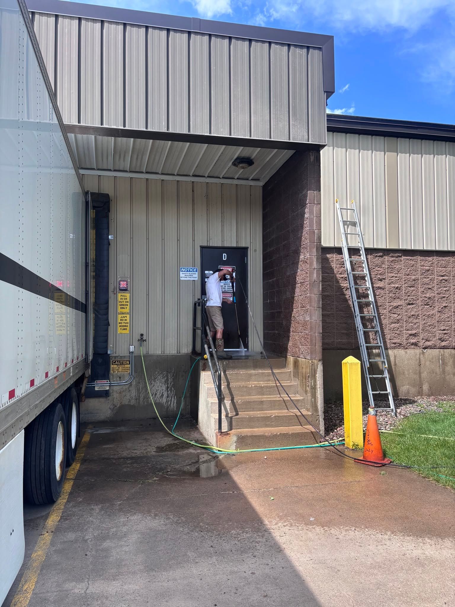 Person standing at a dark doorway beside a warehouse loading dock and truck bay