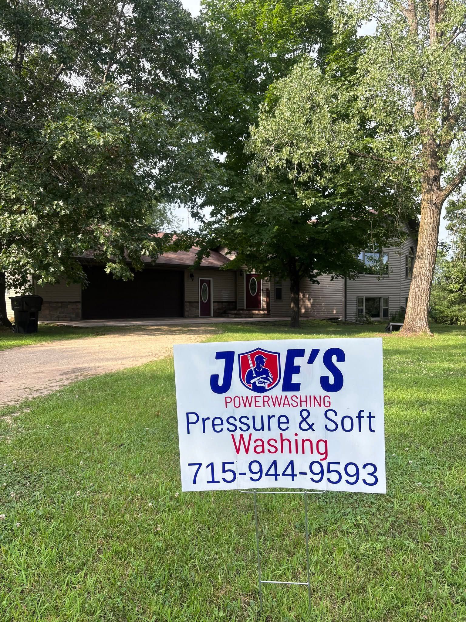 Joe's Pressure & Soft Washing sign on a lawn in front of a house with trees and a driveway.