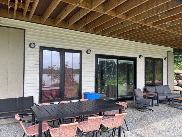 Covered patio with black and glass tables, wicker chairs, and sliding doors under a wood ceiling
