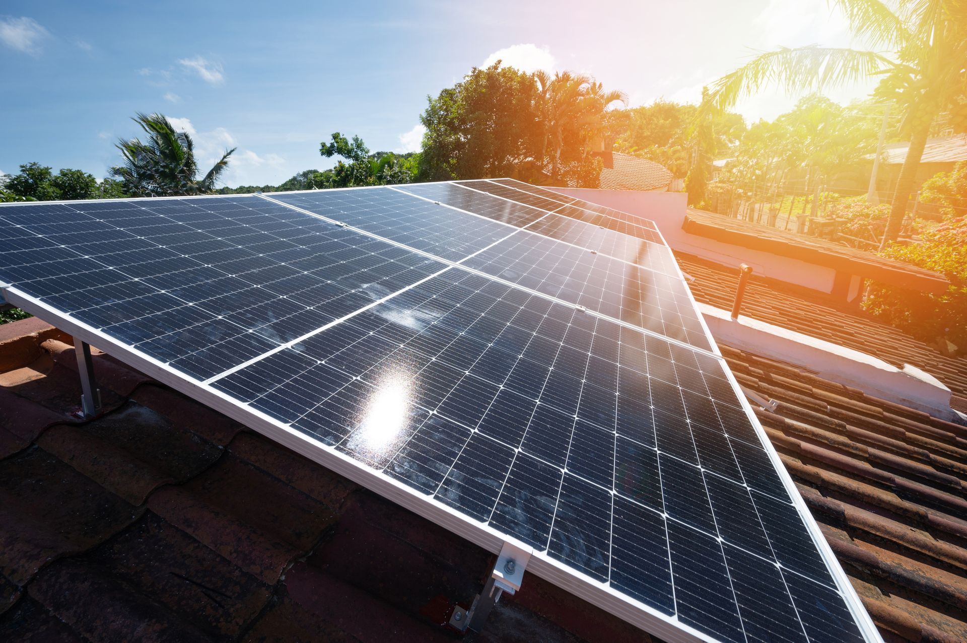 Solar panels on a rooftop at sunset with bright sun glare and blue sky