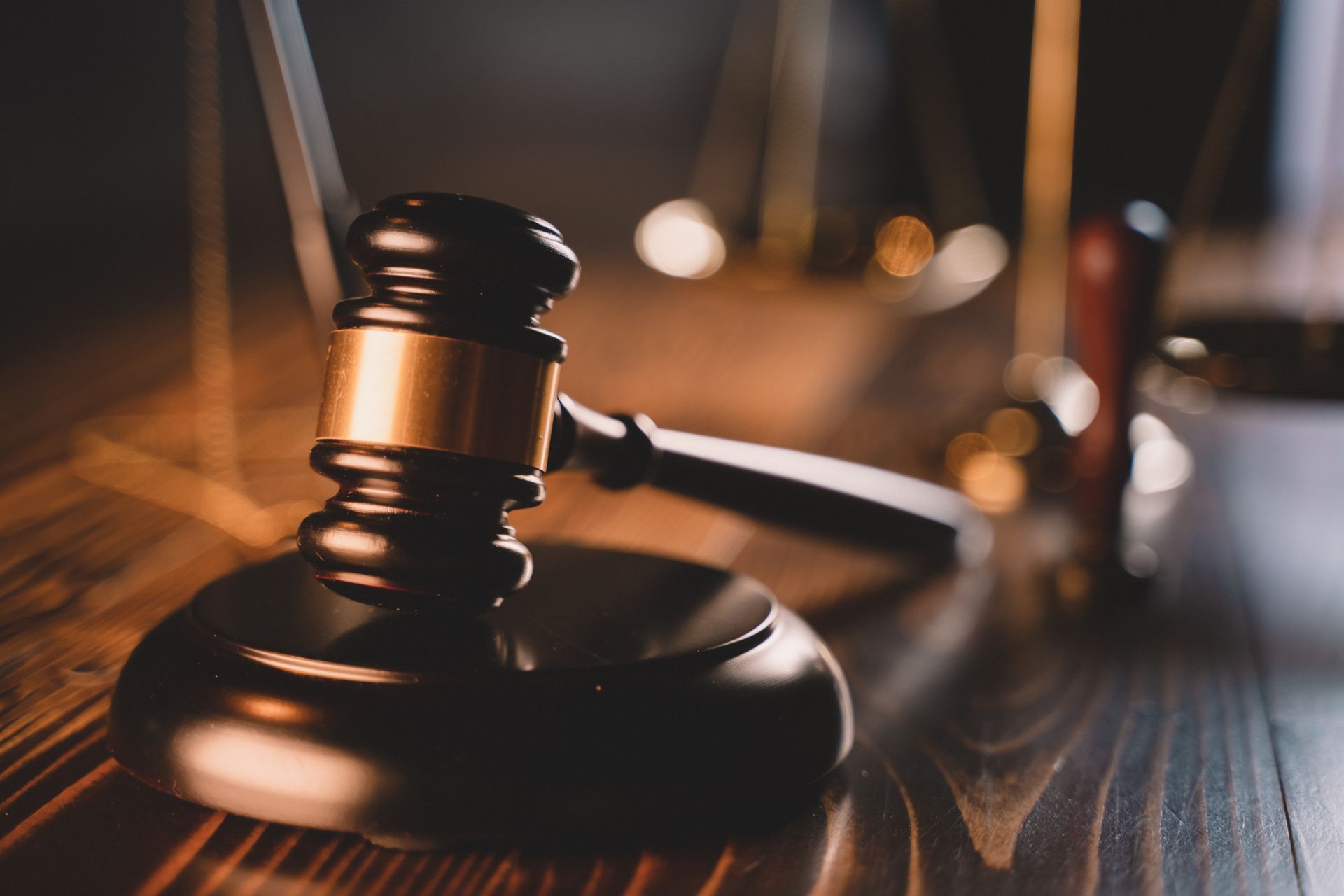 Wooden gavel and sound block on a dark wooden table, blurred background.