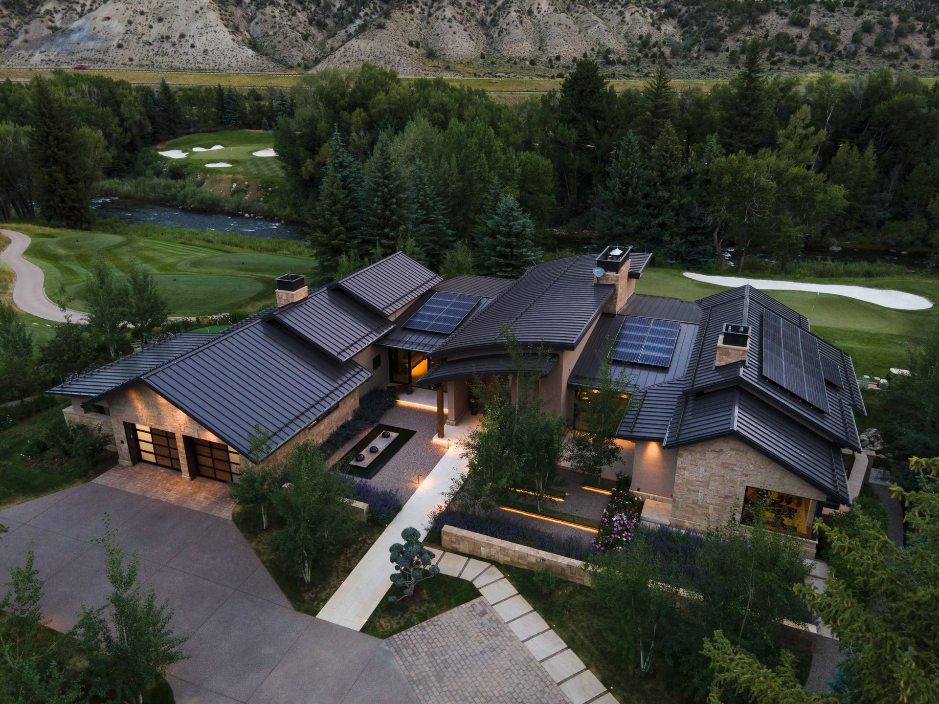 An aerial view of a large house surrounded by trees and a golf course.