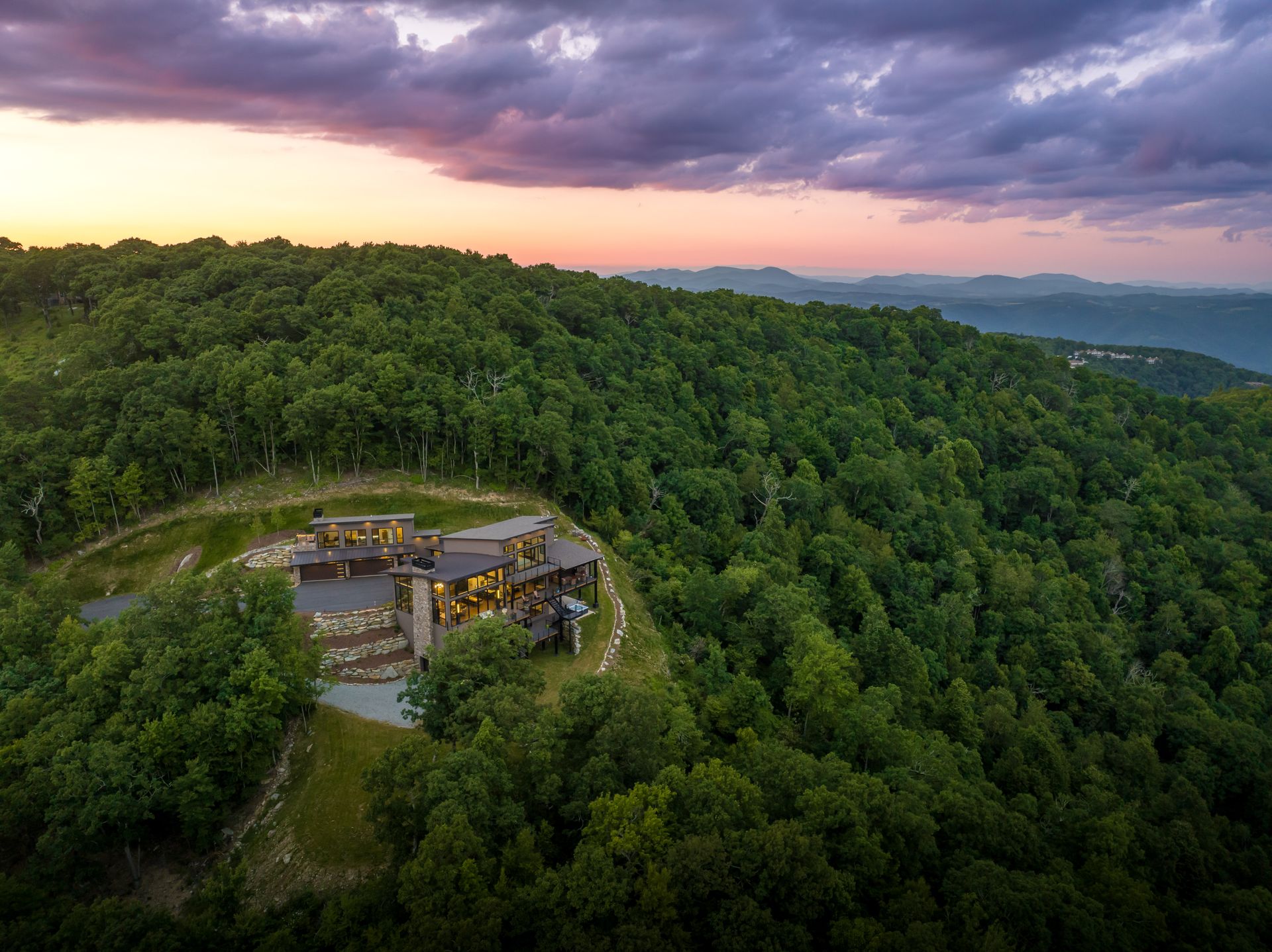 An aerial view of a house on top of a hill surrounded by trees.