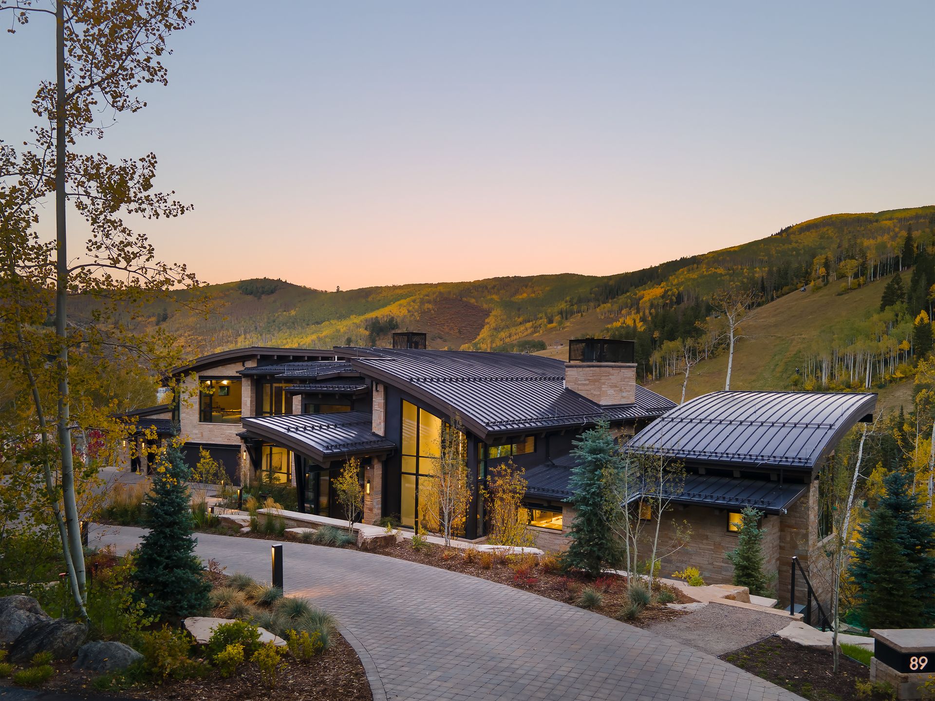 A large house is sitting on top of a hill in the middle of a forest.