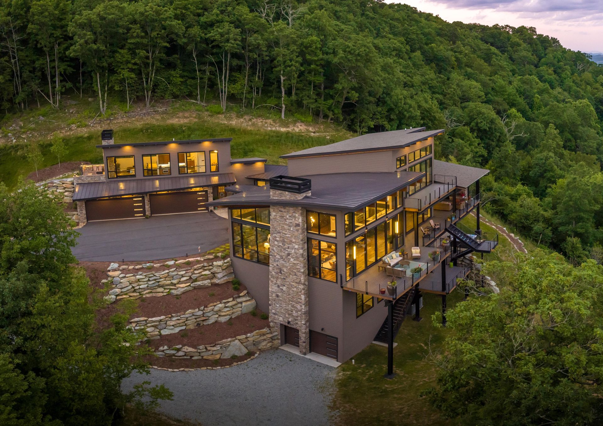 An aerial view of a large house on top of a hill surrounded by trees.