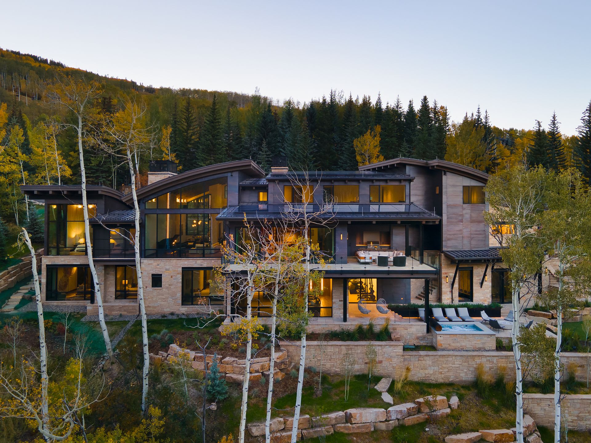 A large house sits on top of a hill surrounded by trees